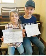 Kendra and Joel Schneider showing off their tractor drawings.